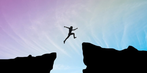 Man jump through the gap between hill.man jumping over cliff on